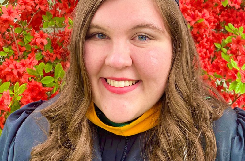 A smiling woman wearing a commencement gown.